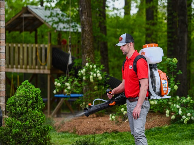 Man Spreading Yard With Mosquito Killing Treatment