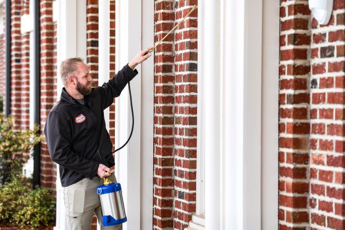 City Wide Exterminating Team Member Spraying House